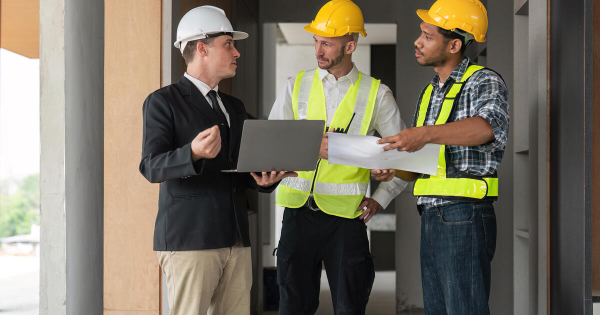 Professional construction engineers team using blueprint of project plan.